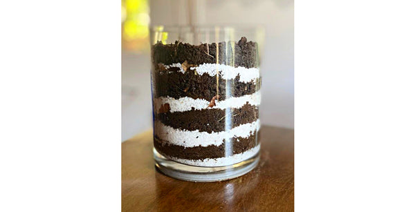 A science experiment layered with soil and sand in a clear container.