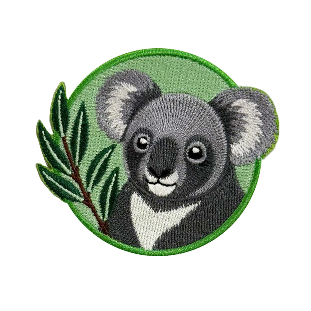 An embroidered patch featuring a cute koala bear face with gray and white fur, a green leafy branch on the left, and a green embroidered border on a white background.