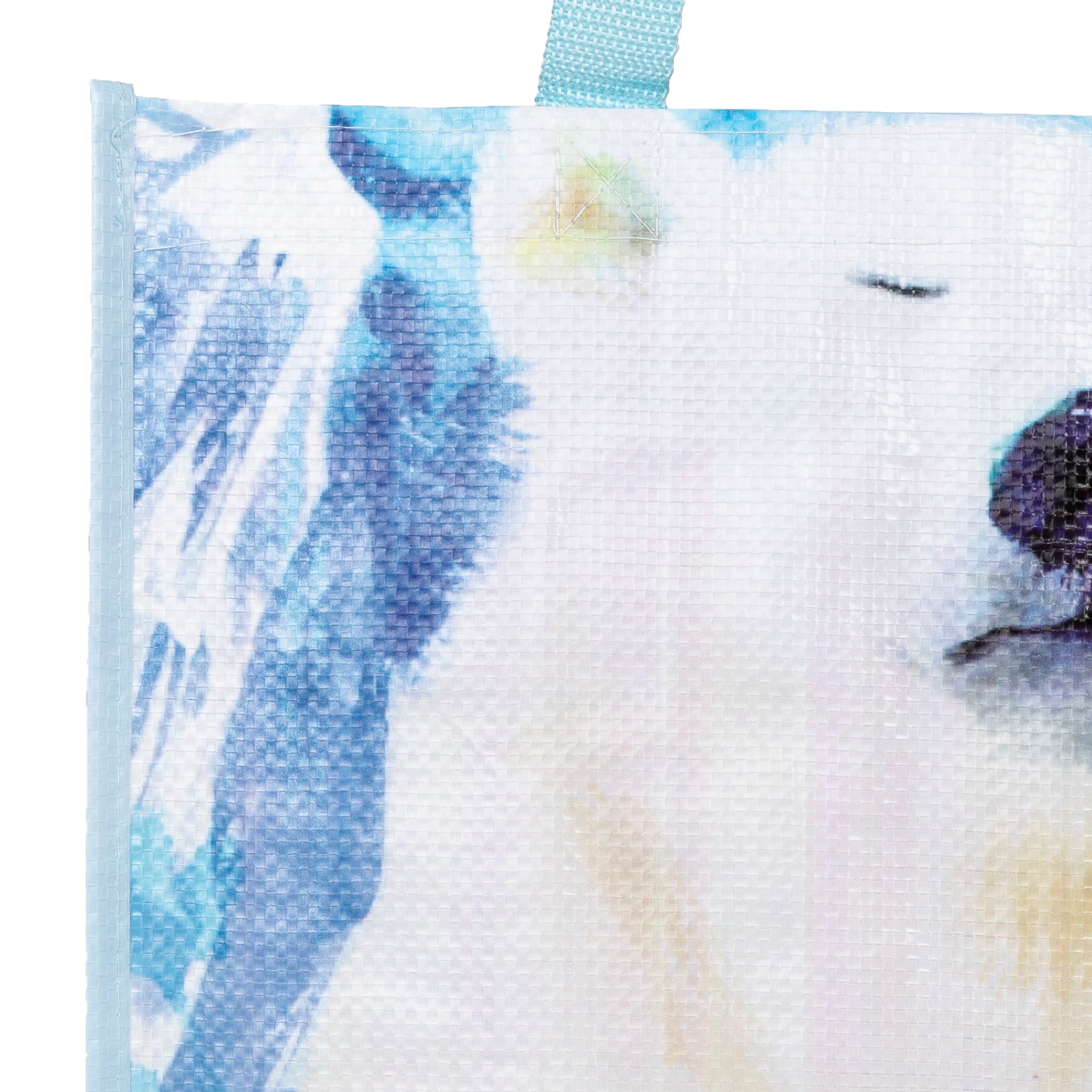Close-up of a white polar bear bag with blue and yellow accents on a textured background